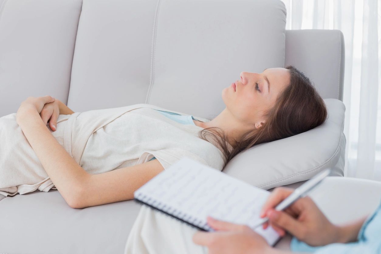 Person reclined on couch, receiving hypnotherapy